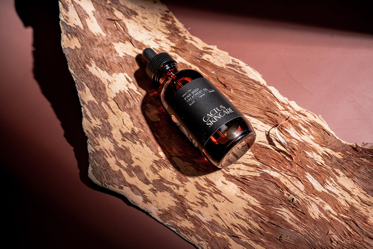 Pink Body Treatment Oil amber dropper bottle resting on natural bark