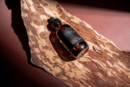 Pink Body Treatment Oil amber dropper bottle resting on natural bark
